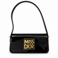 Glossy black shoulder bag with gold Miss Dior plaque on a white background